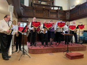 Saxophonic members with red banners some stading on raised platform